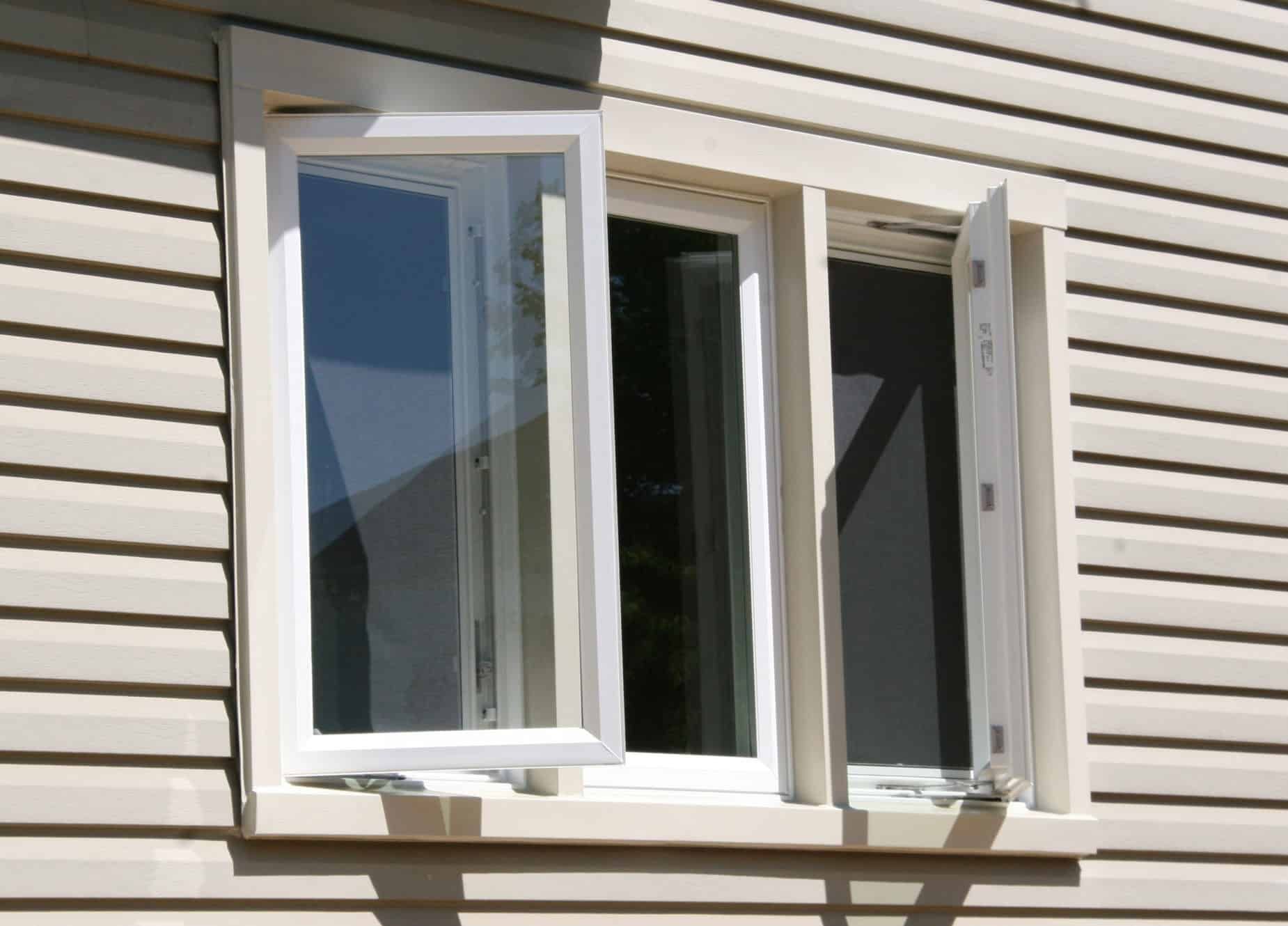 White-framed casement window, partially open, on a beige siding wall.