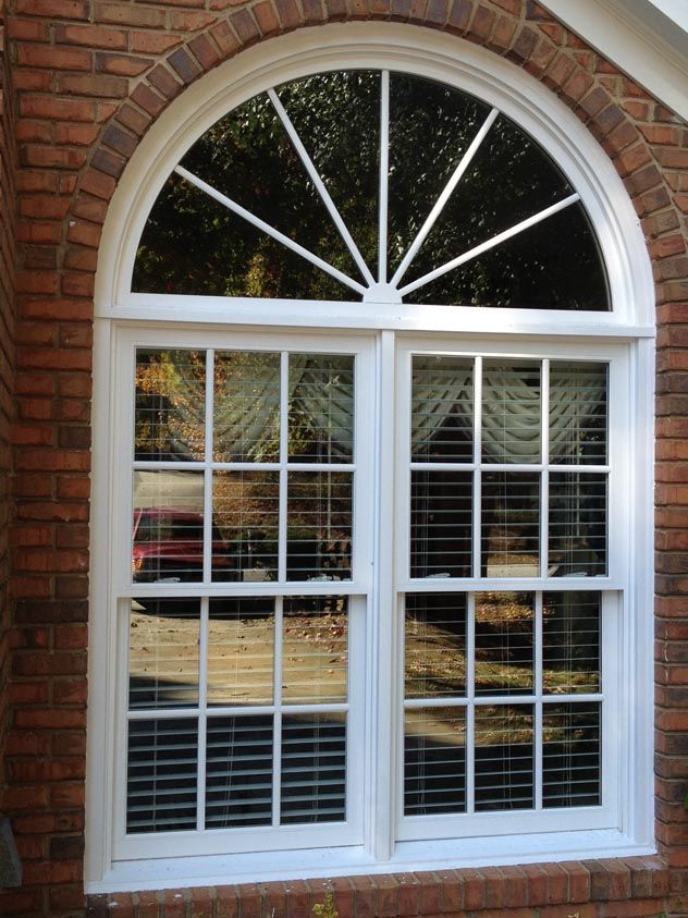 White window with an arched top in a brick wall.