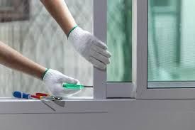 Person in white gloves using a screwdriver to repair a window frame.