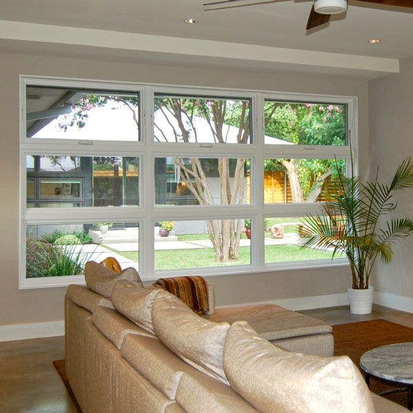 Living room with large window overlooking a backyard, beige couch, and a potted plant.