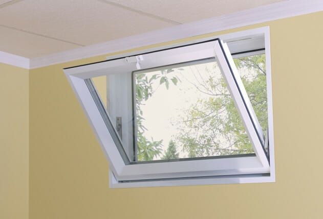 Open, white-framed window in a yellow wall, revealing a view of green trees.