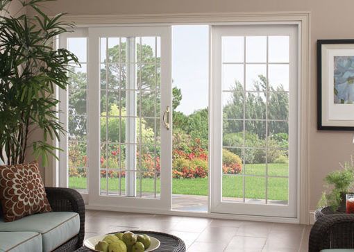 White patio doors open to a green yard, viewed from a living room with a sofa and coffee table.