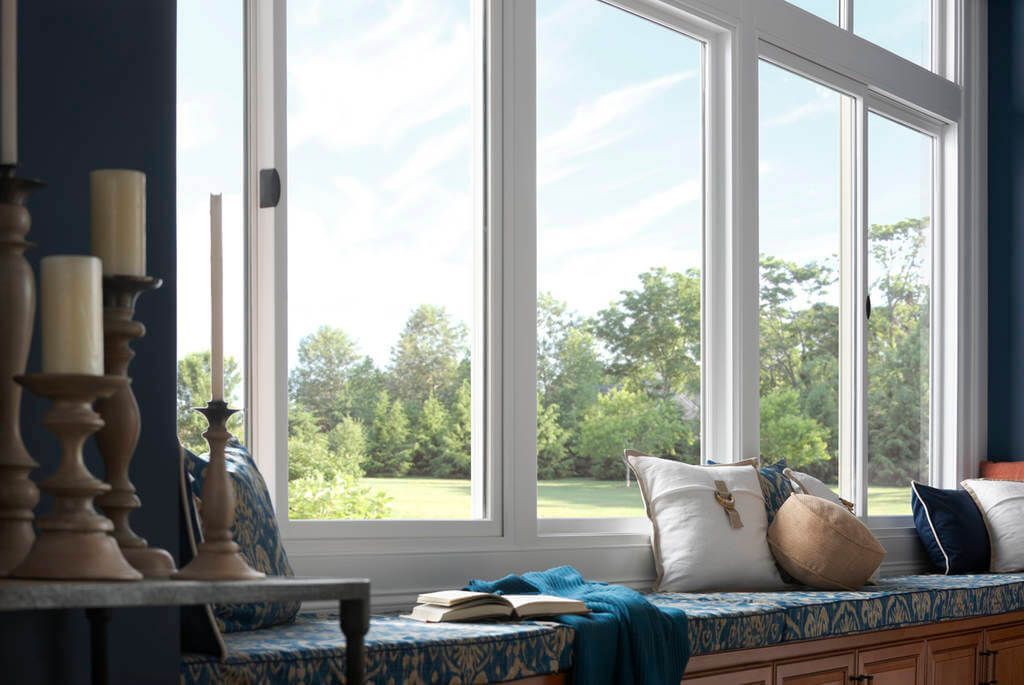 A sunny window seat with blue cushions and a view of a green tree-filled yard.