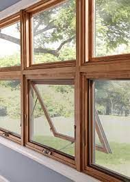 Wooden framed awning windows, one partially open, showing a green outdoor view.