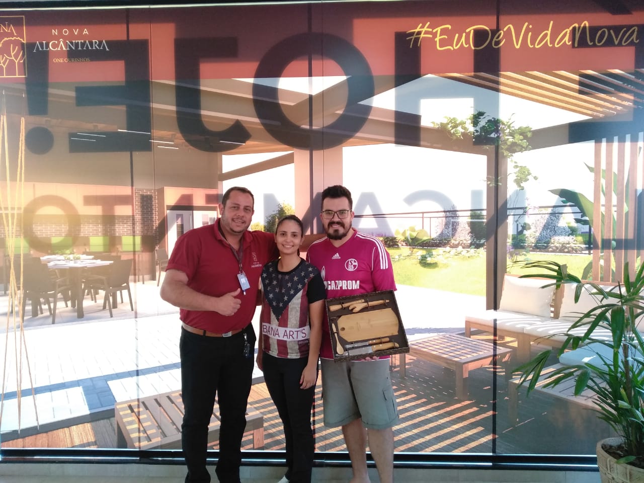 Um grupo de pessoas posa para uma foto em frente a uma placa que diz