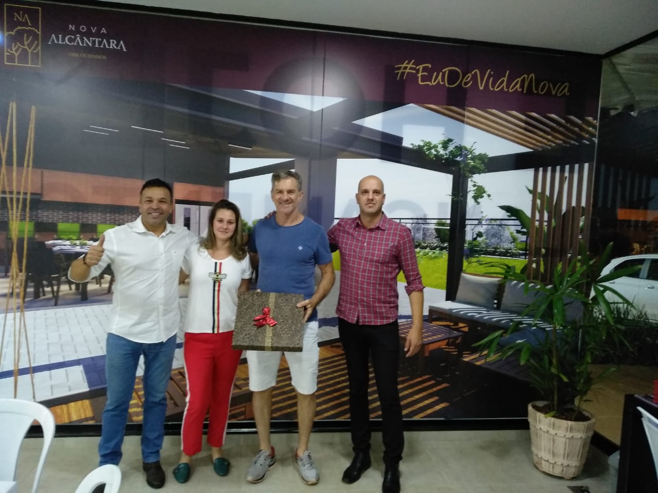 Um grupo de pessoas posando para uma foto em frente a uma parede que diz nova alcampina