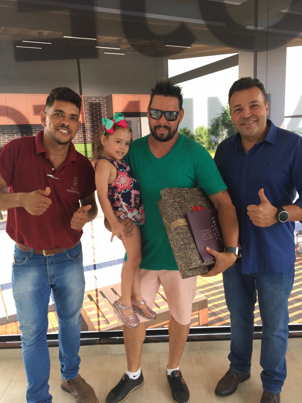 Um homem de camisa verde está segurando uma menina