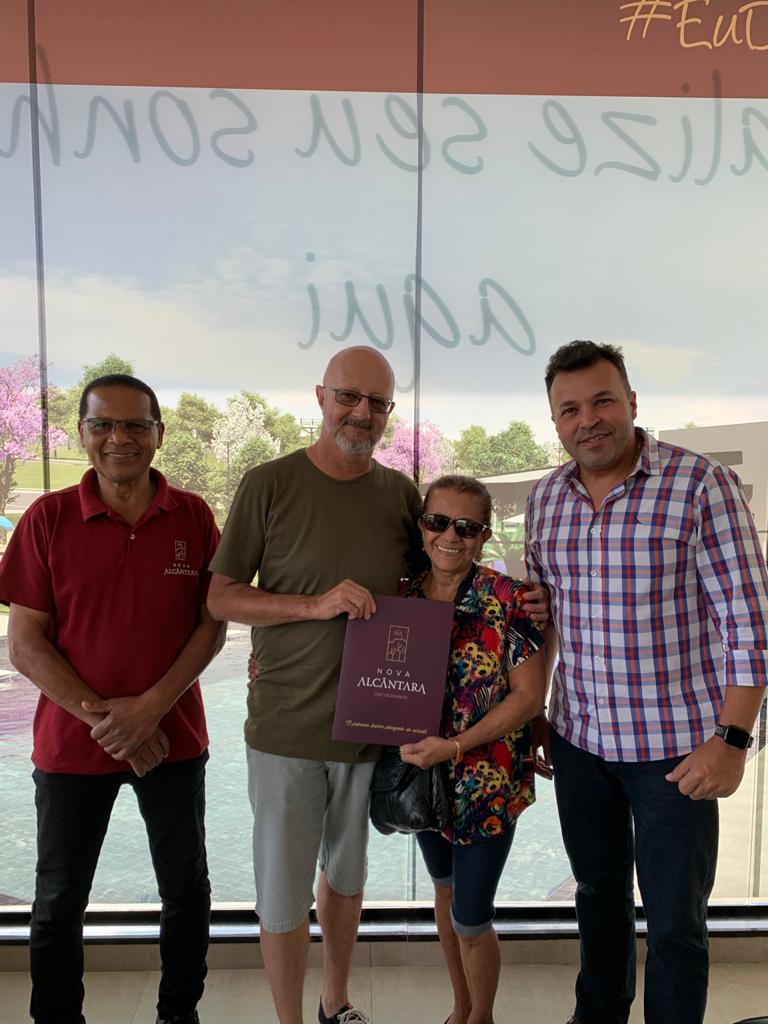 Um grupo de pessoas posa para uma foto em frente a uma janela.