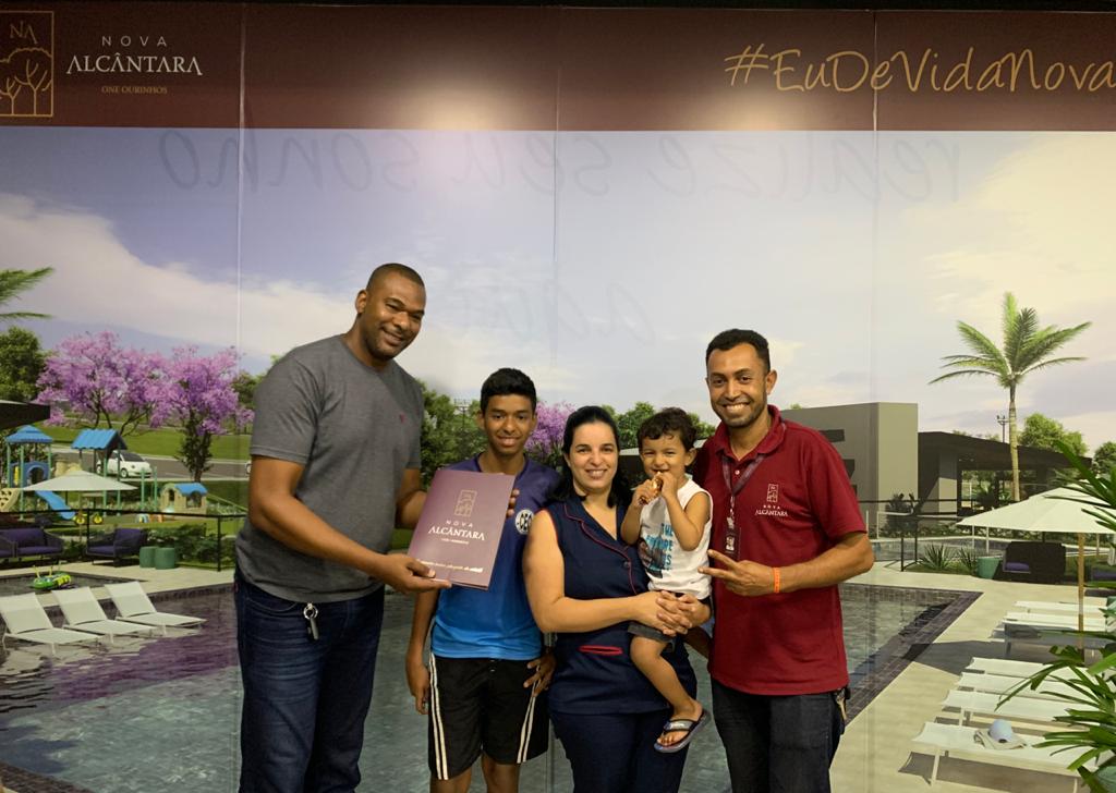 Um grupo de pessoas posa para uma foto em frente a uma parede.