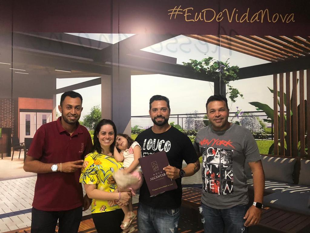 Um grupo de pessoas próximas umas das outras em frente a uma parede.