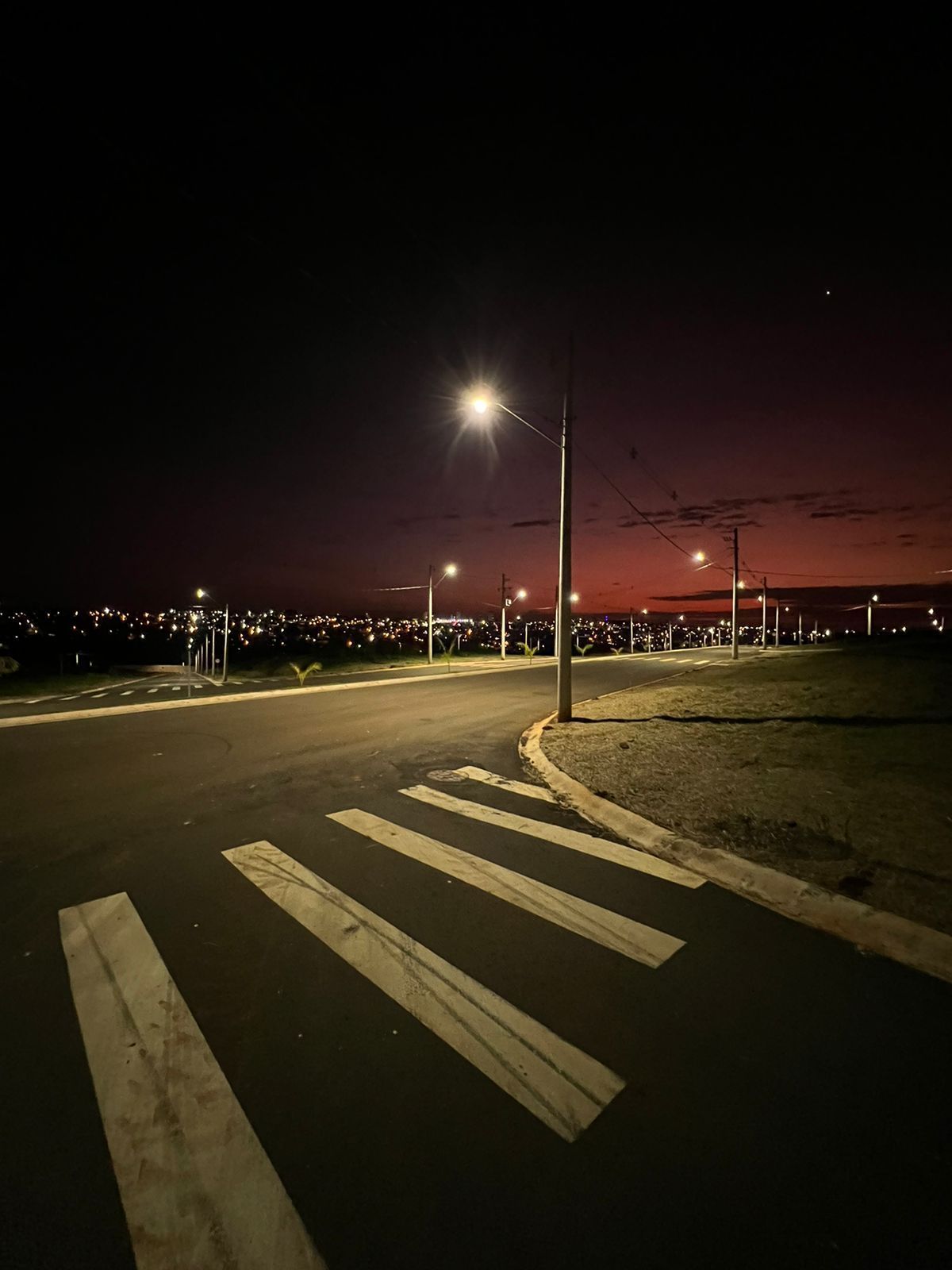 Uma faixa de pedestres em uma rua à noite com uma cidade ao fundo