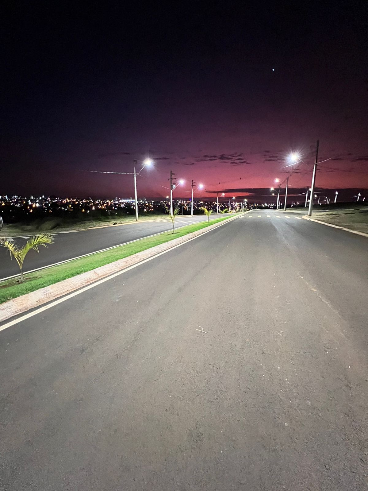 Uma estrada vazia à noite com um pôr do sol ao fundo.