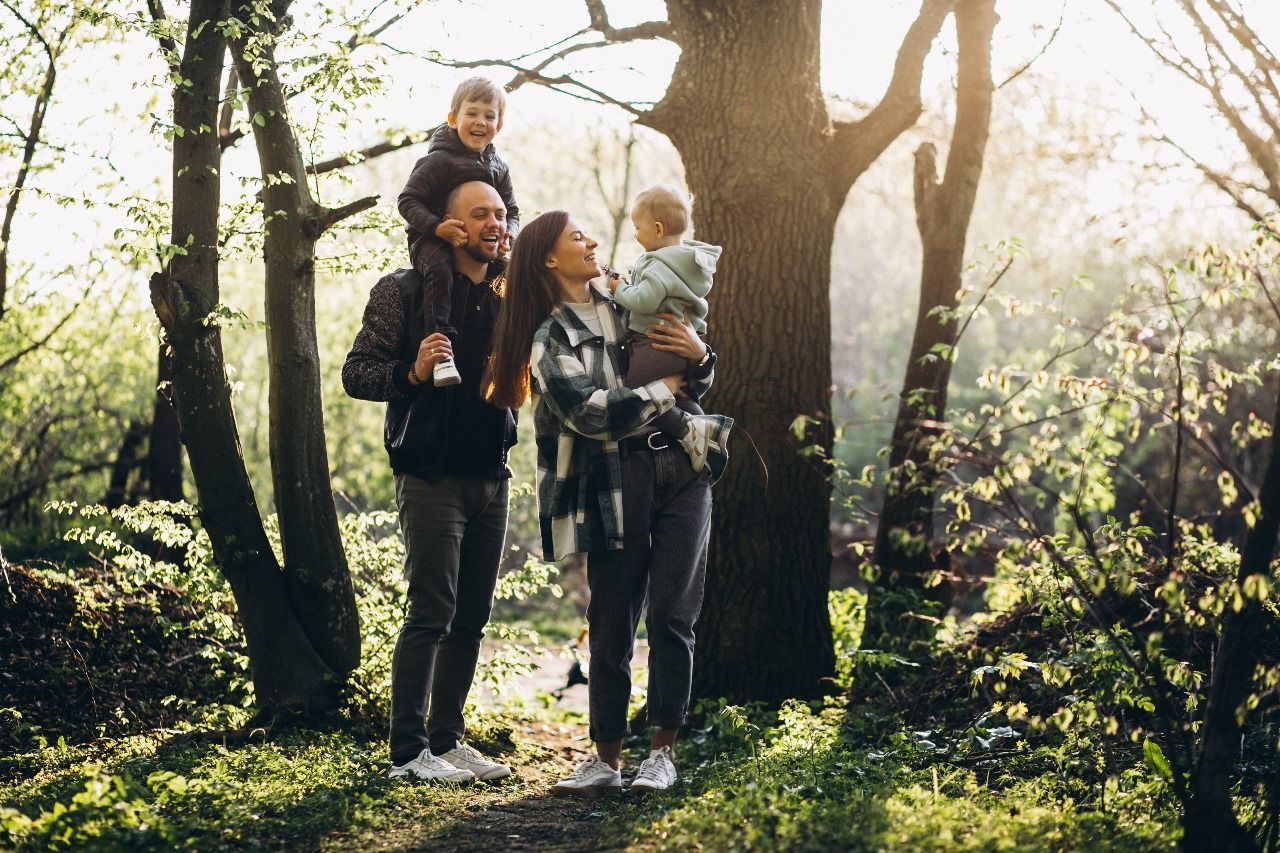 Uma família está na floresta olhando para o céu.