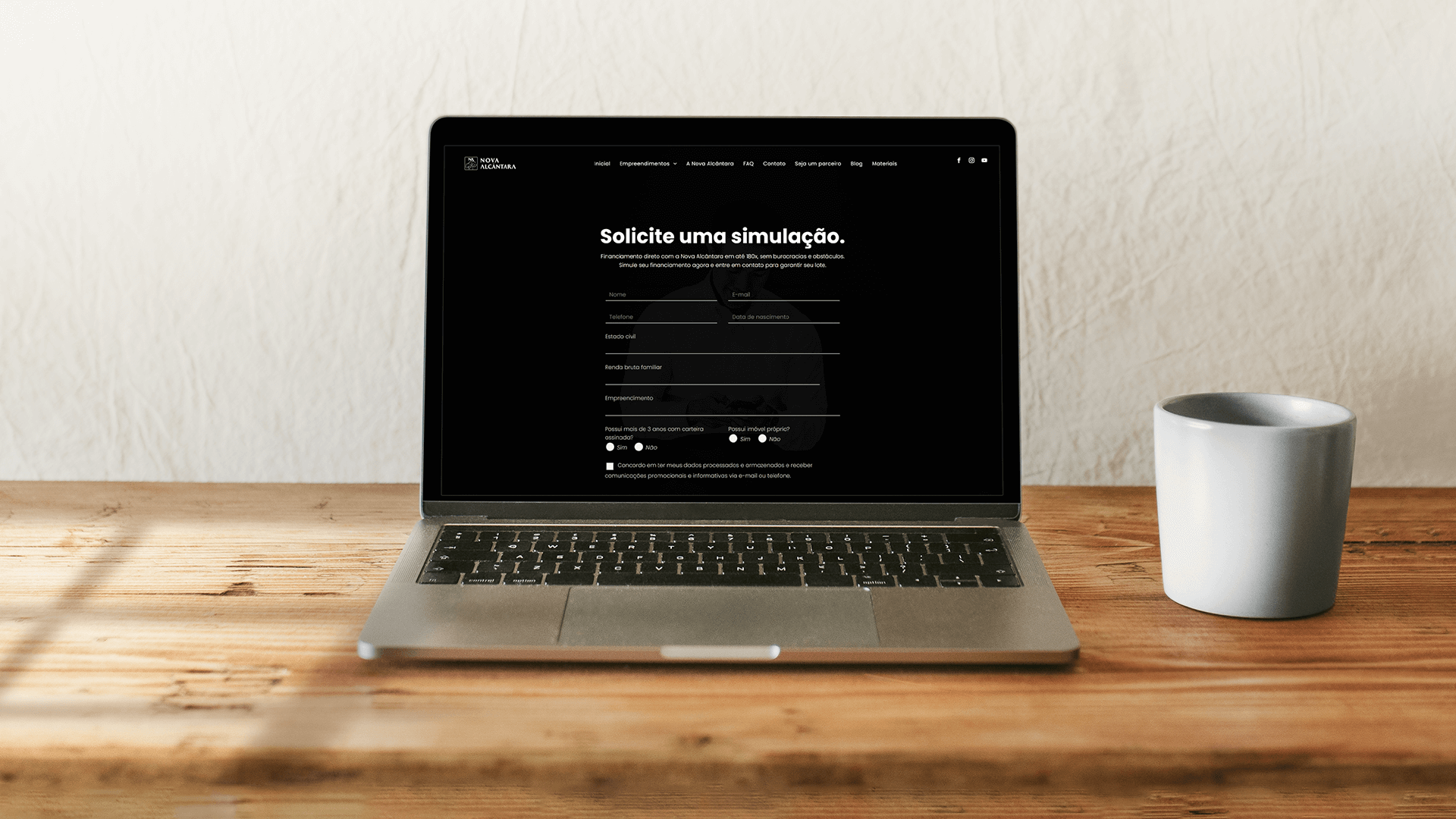 Um laptop está aberto sobre uma mesa de madeira ao lado de uma xícara de café.