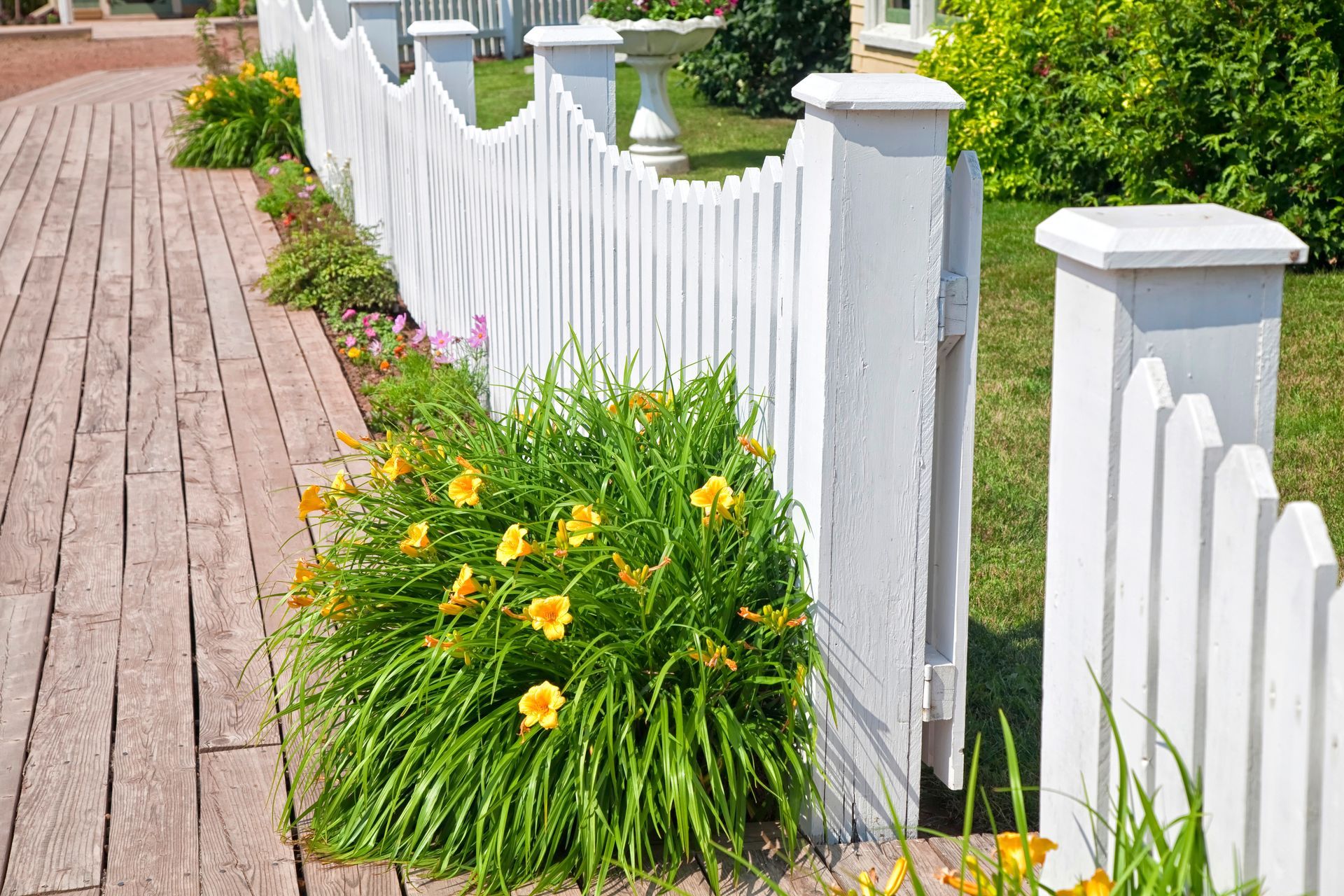 A pristine white picket fence surrounding a charming garden with colorful flowers in full bloom.