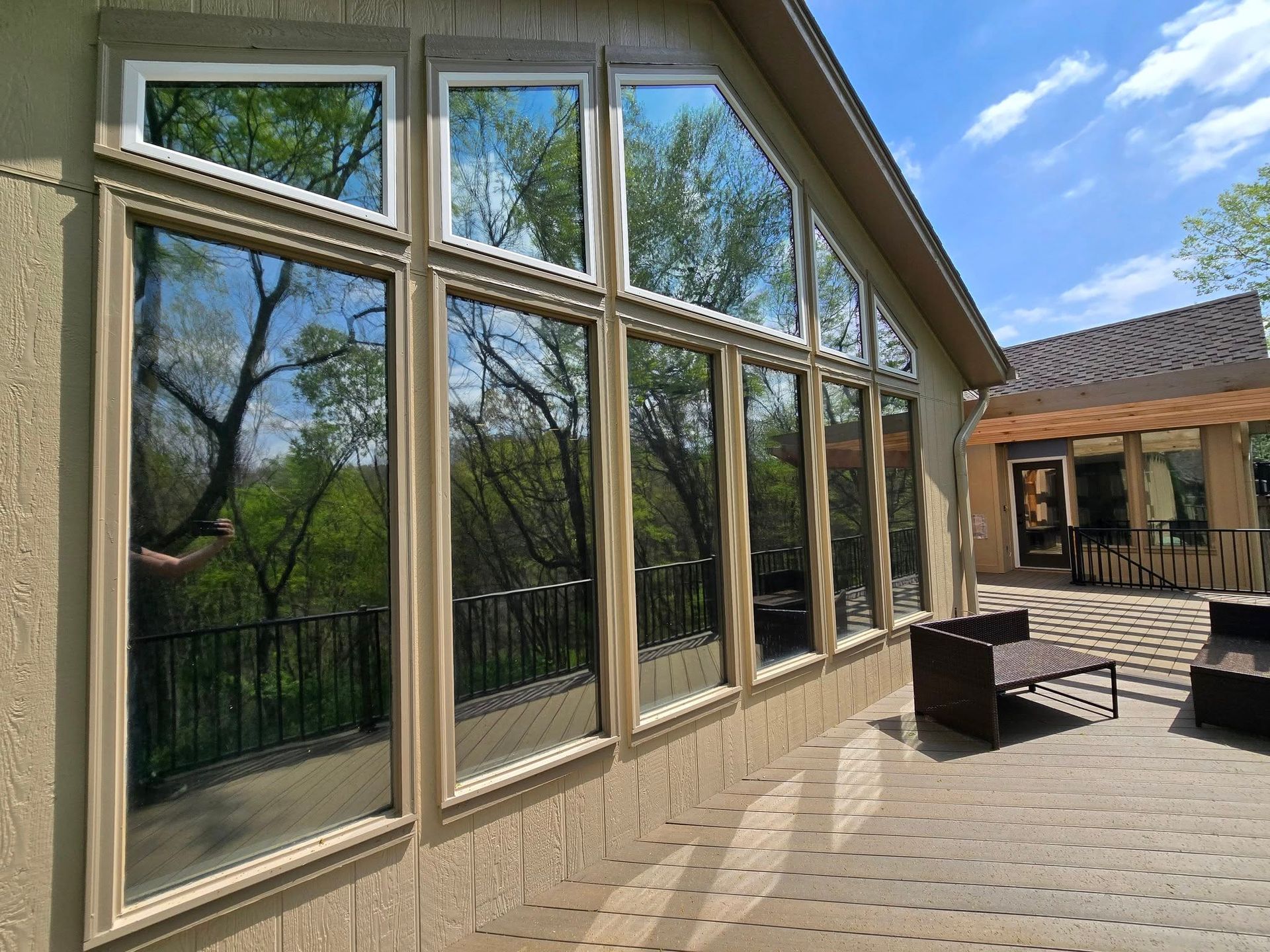 A house with a lot of windows and trees reflected in the windows