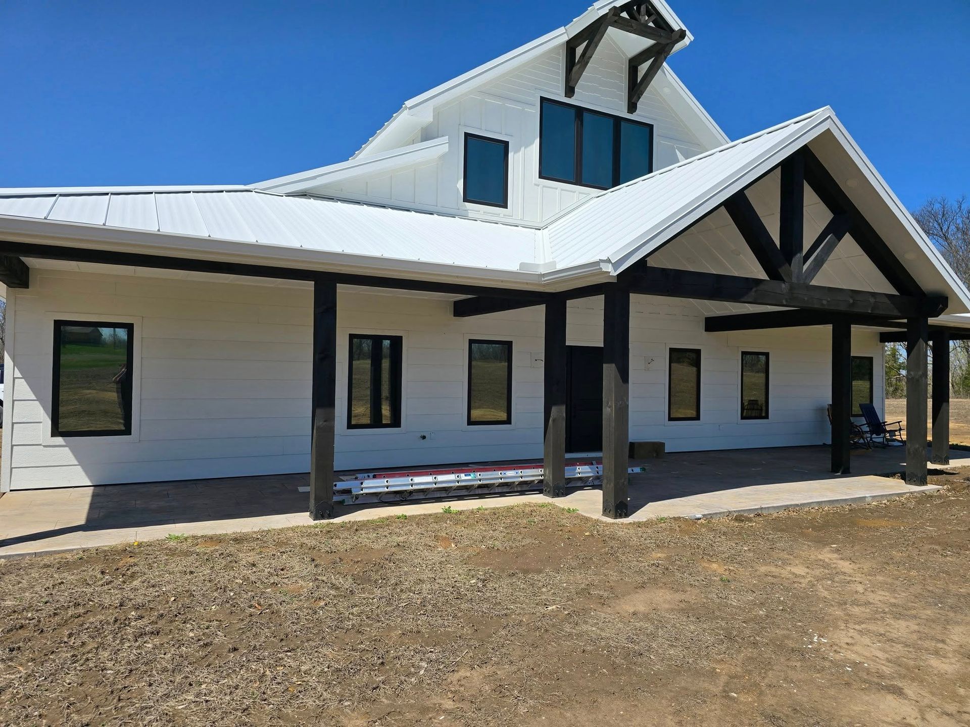 A large white house with a black porch and a blue sky in the background.