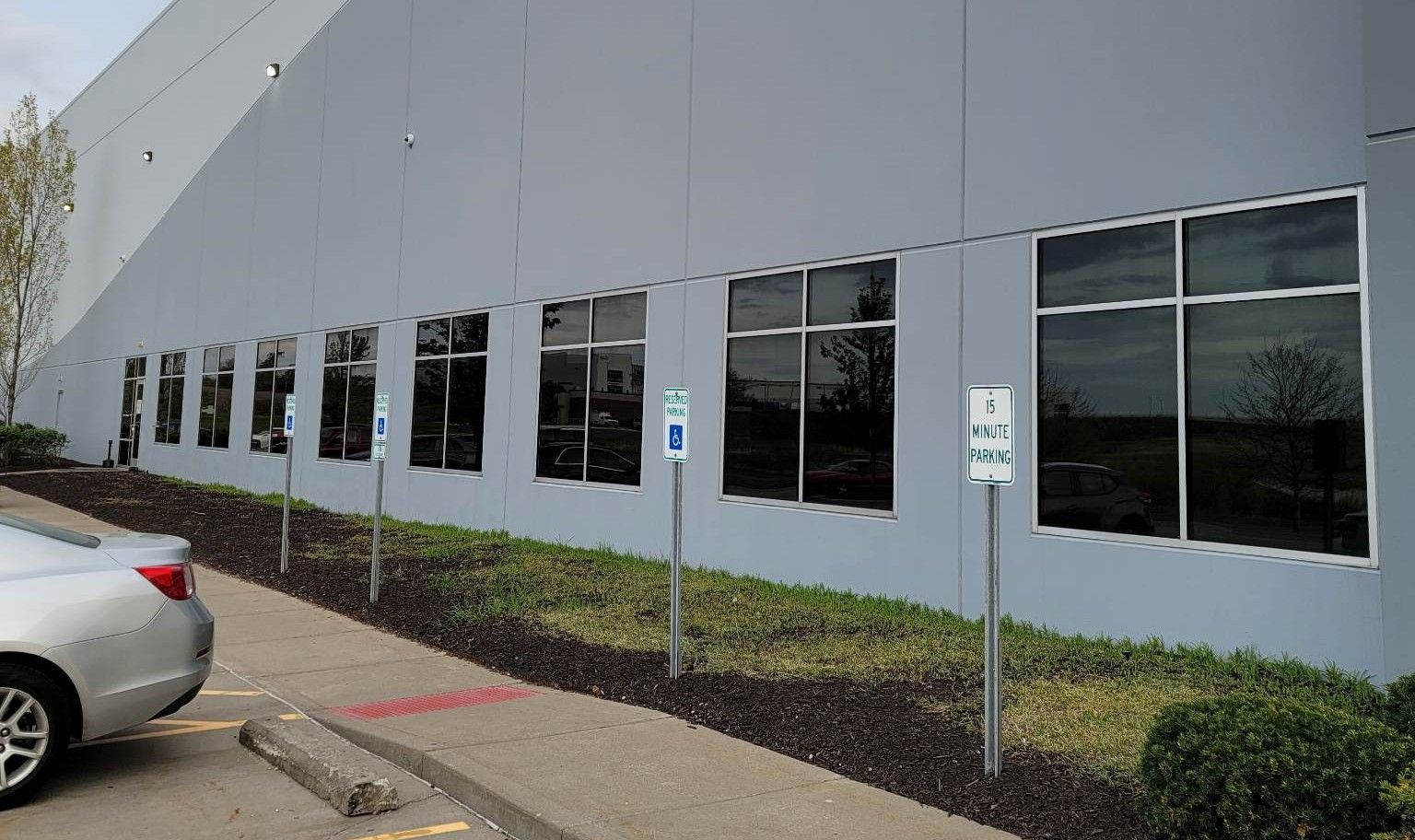 A car is parked in front of a large building.