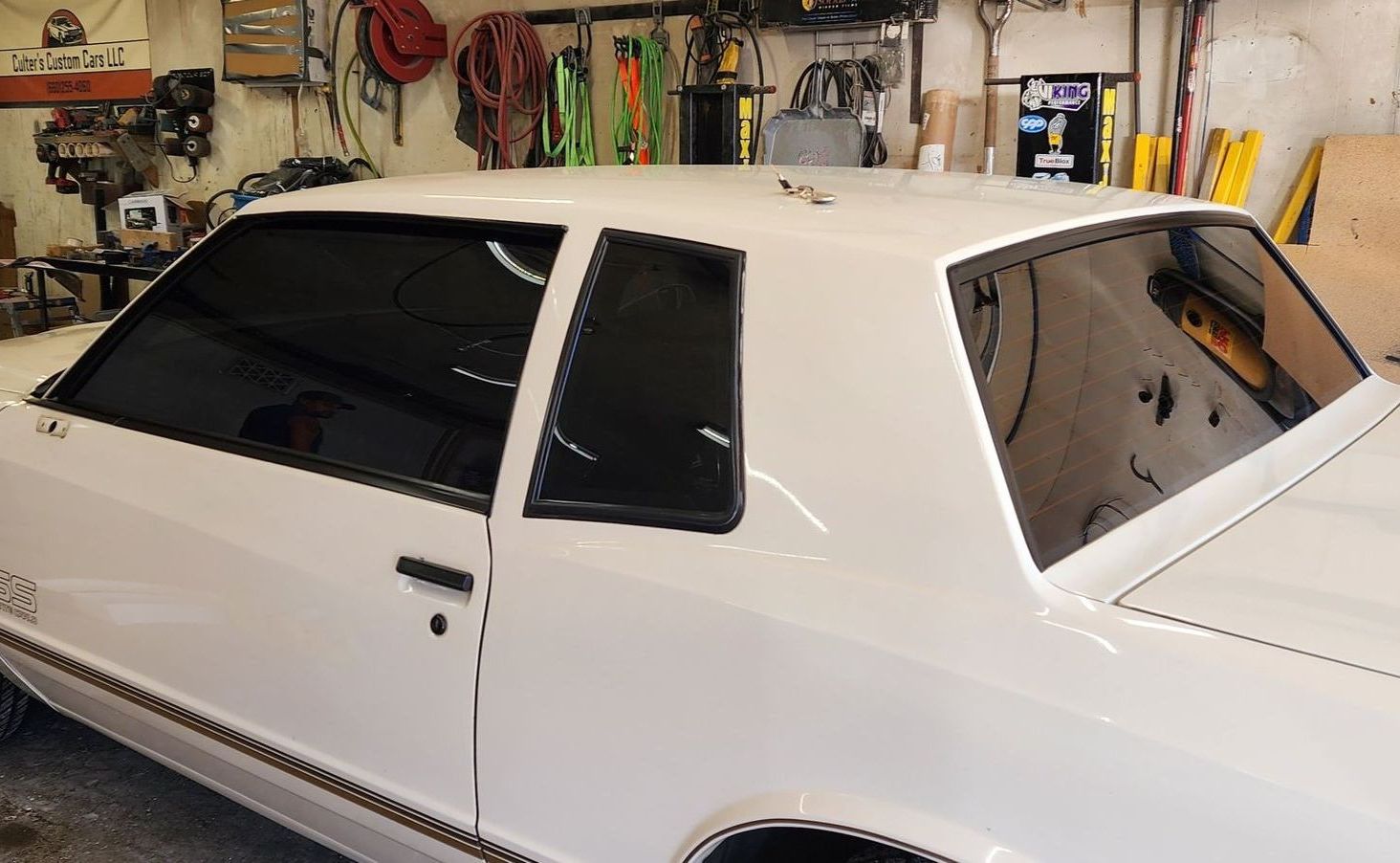 A white car with black windows is parked in a garage.