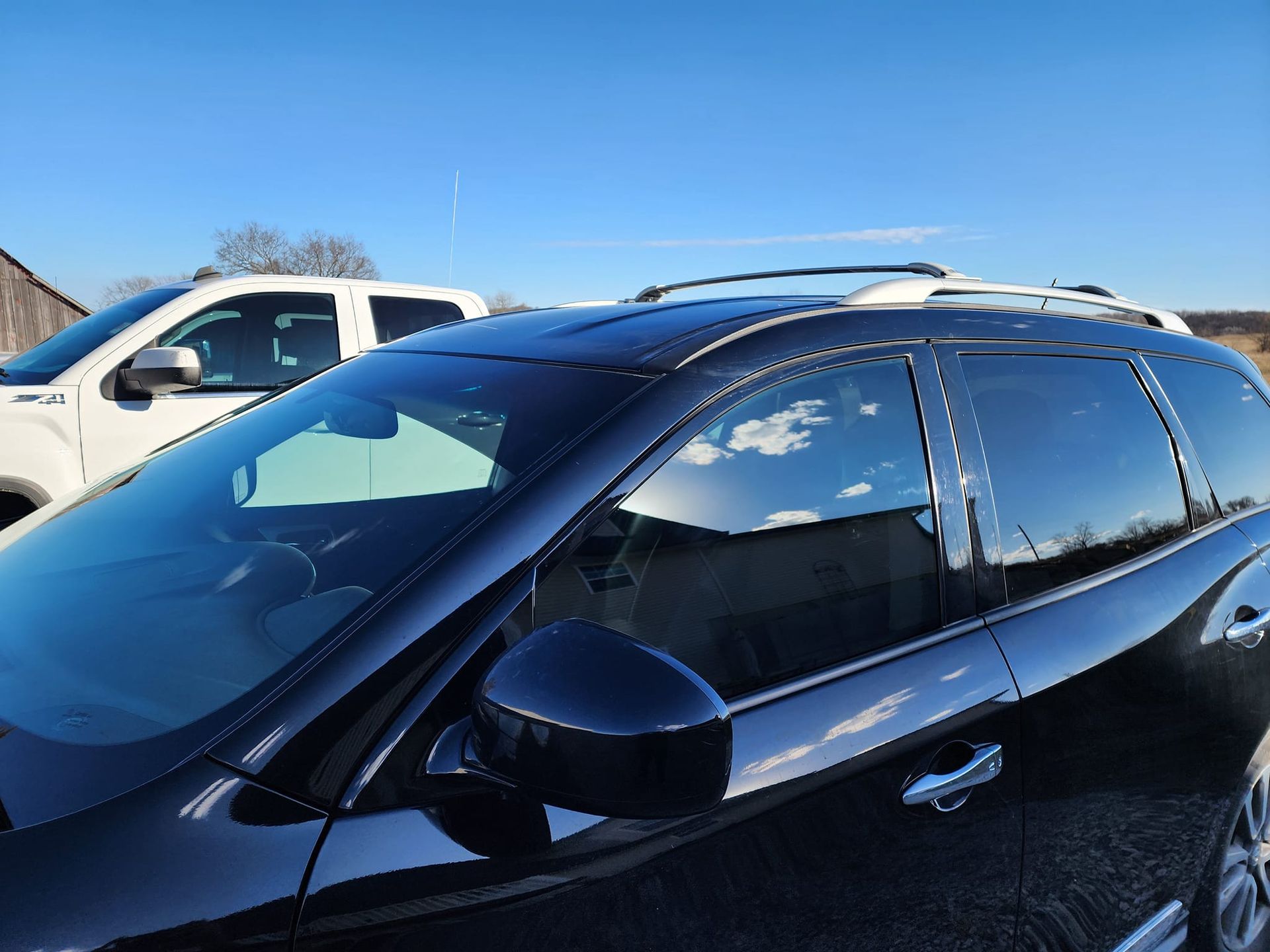 A black suv is parked next to a white truck.