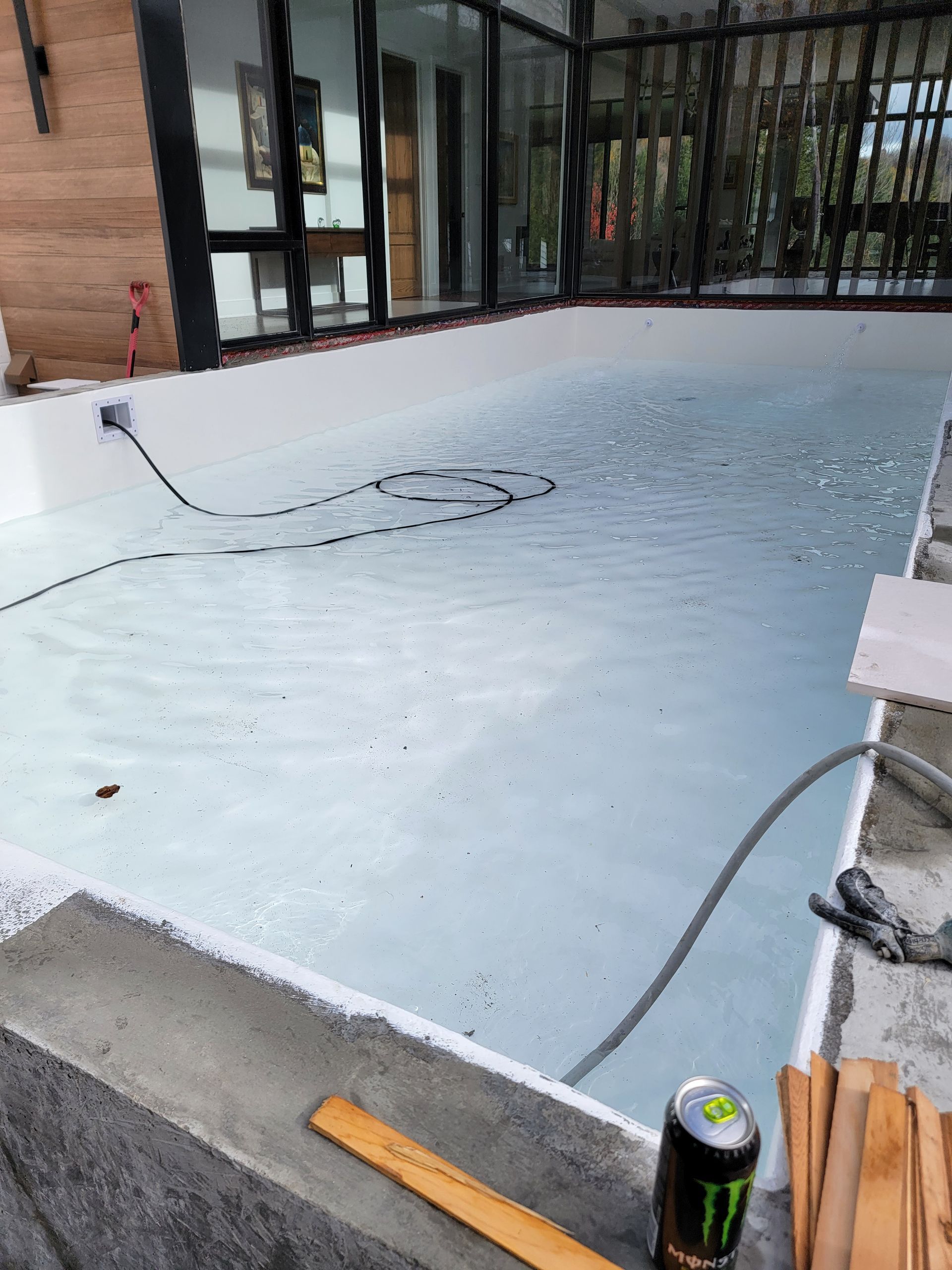 Une canette de boisson énergisante Monster est posée sur le bord d'une piscine.