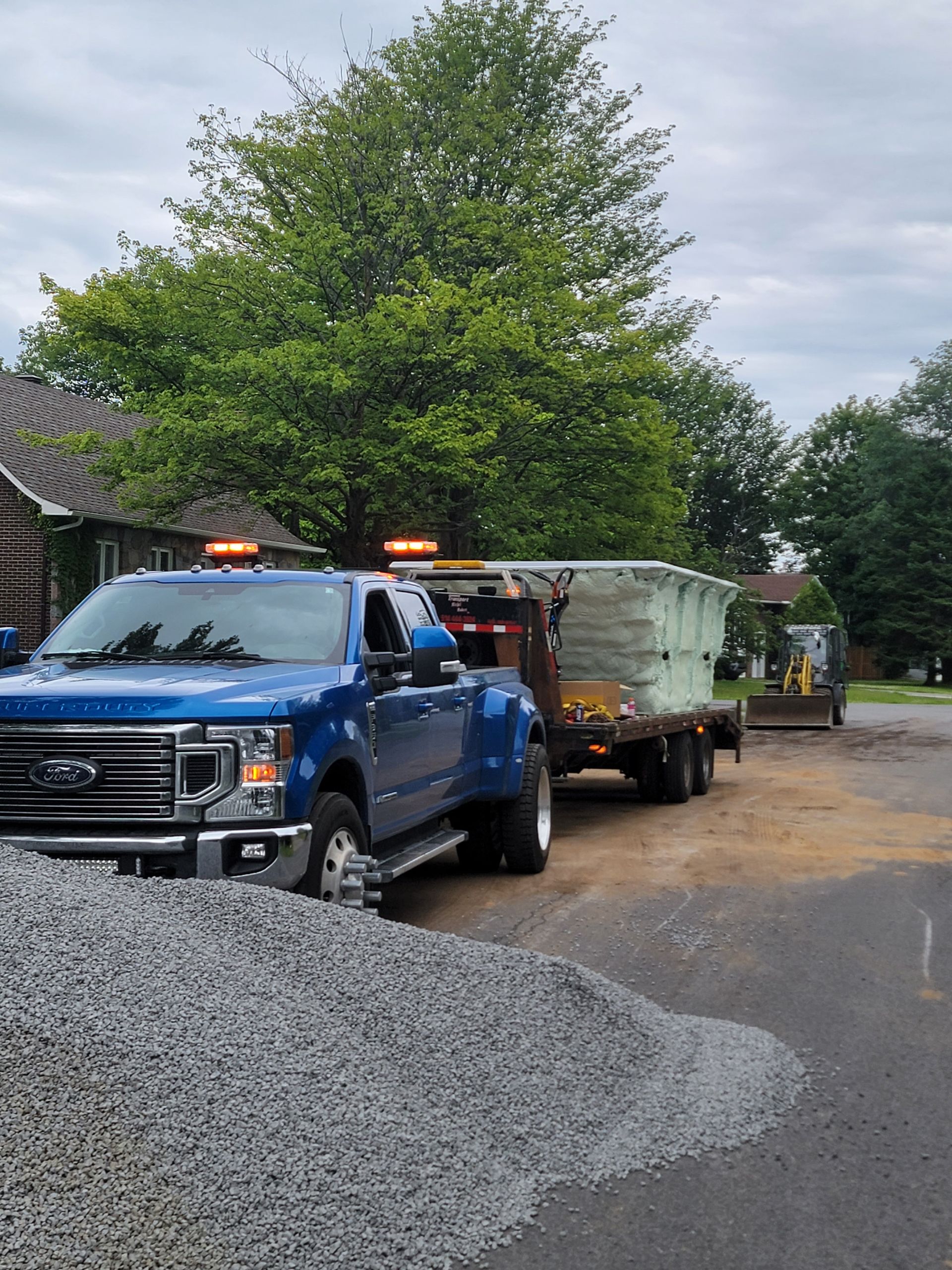 Un camion bleu tracte une remorque avec du gravier dessus