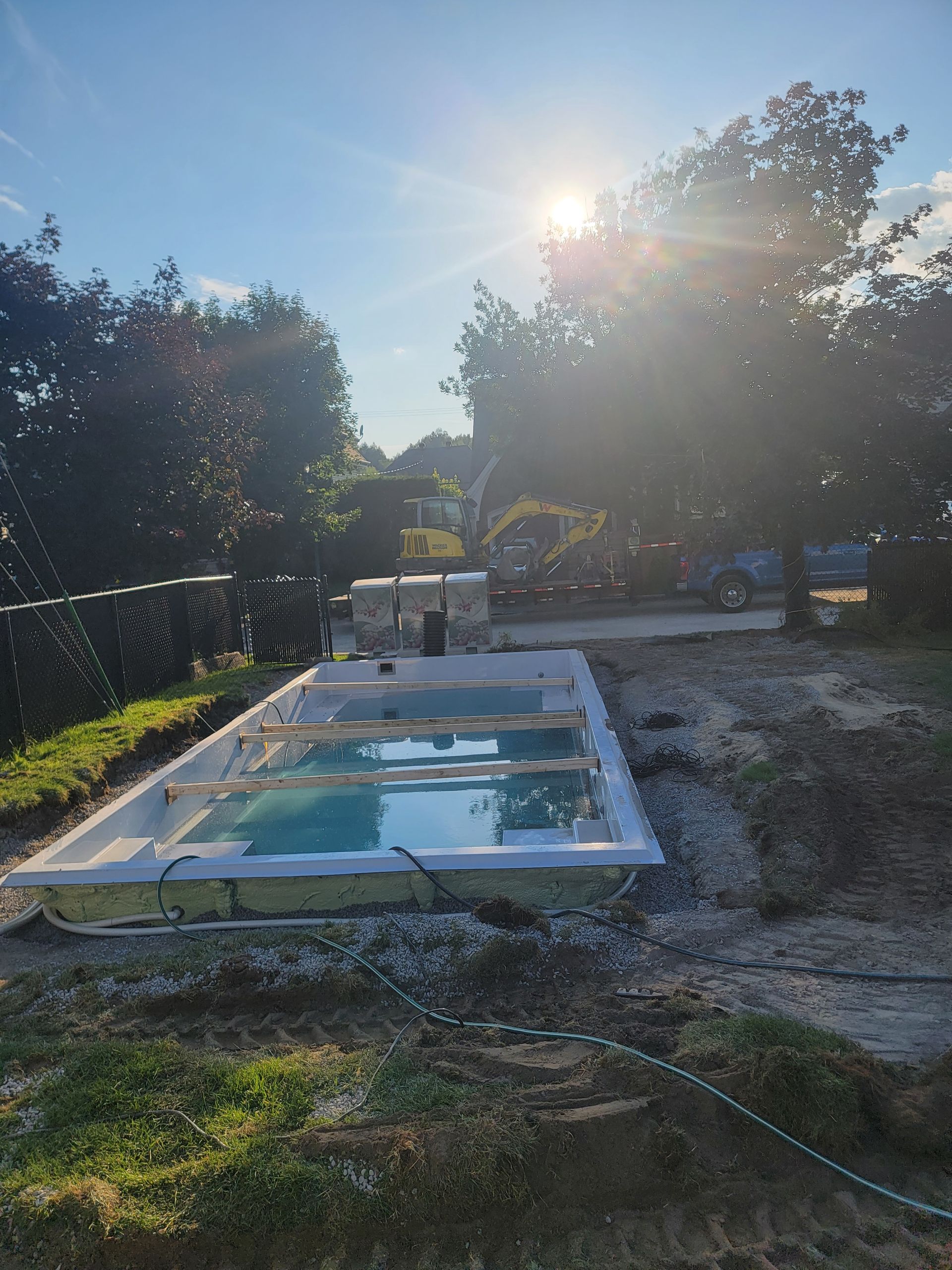Une grande piscine est en cours de construction dans une cour arrière.