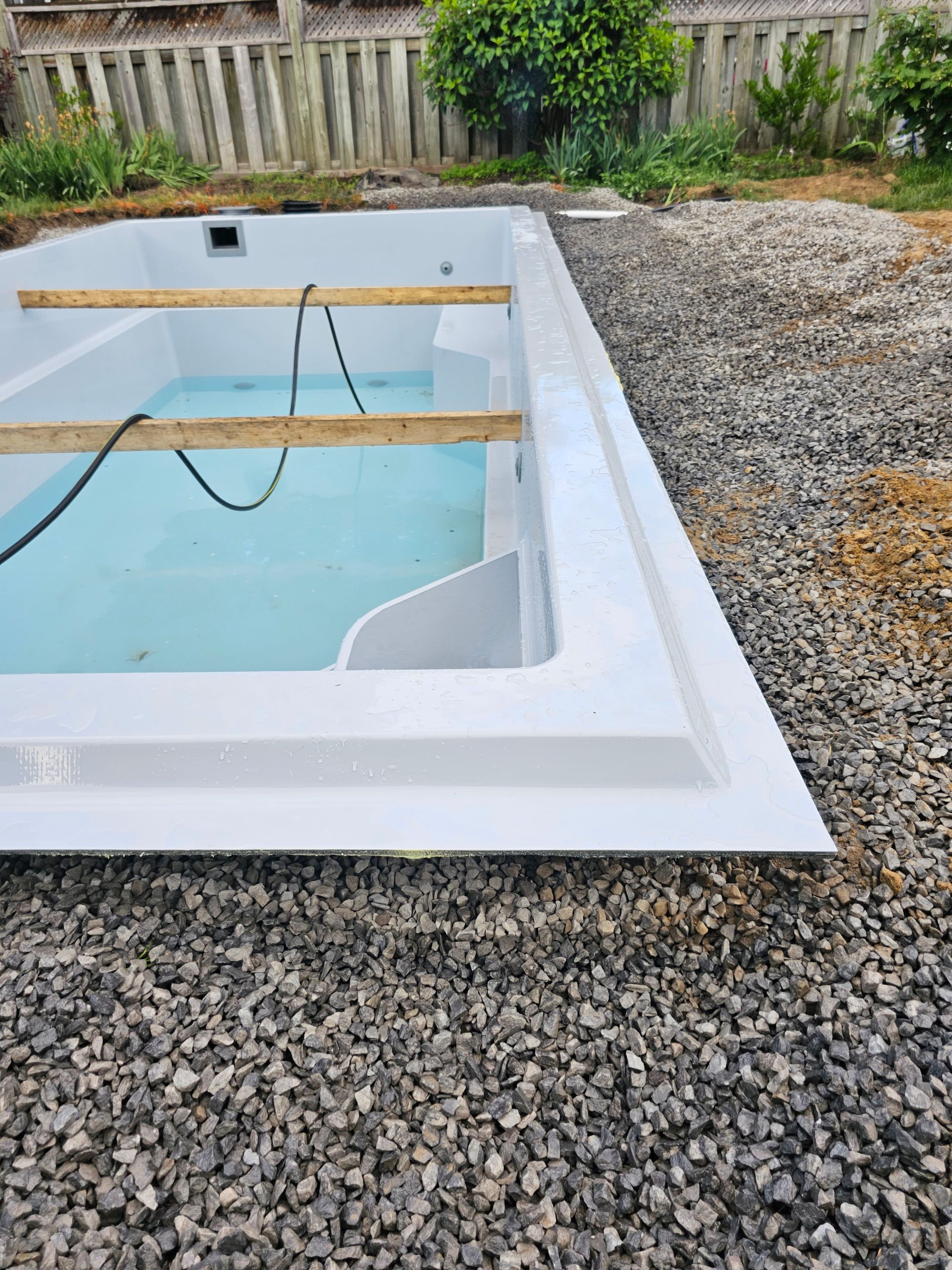 Une piscine blanche est posée sur un tas de gravier.