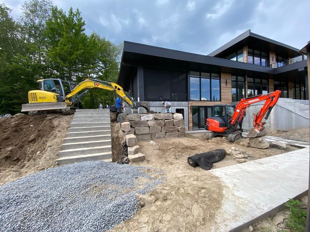 Une grande maison est en construction avec une grande excavatrice devant elle.