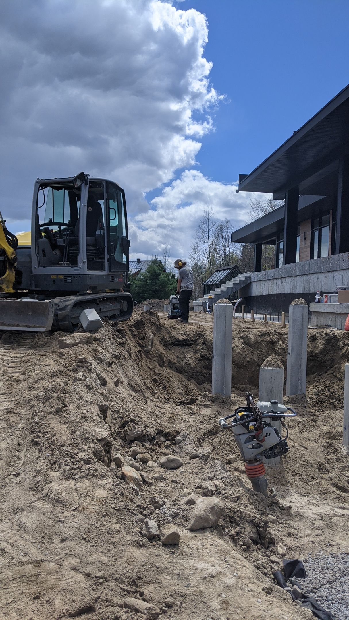 Un bulldozer creuse un trou dans la terre devant une maison.