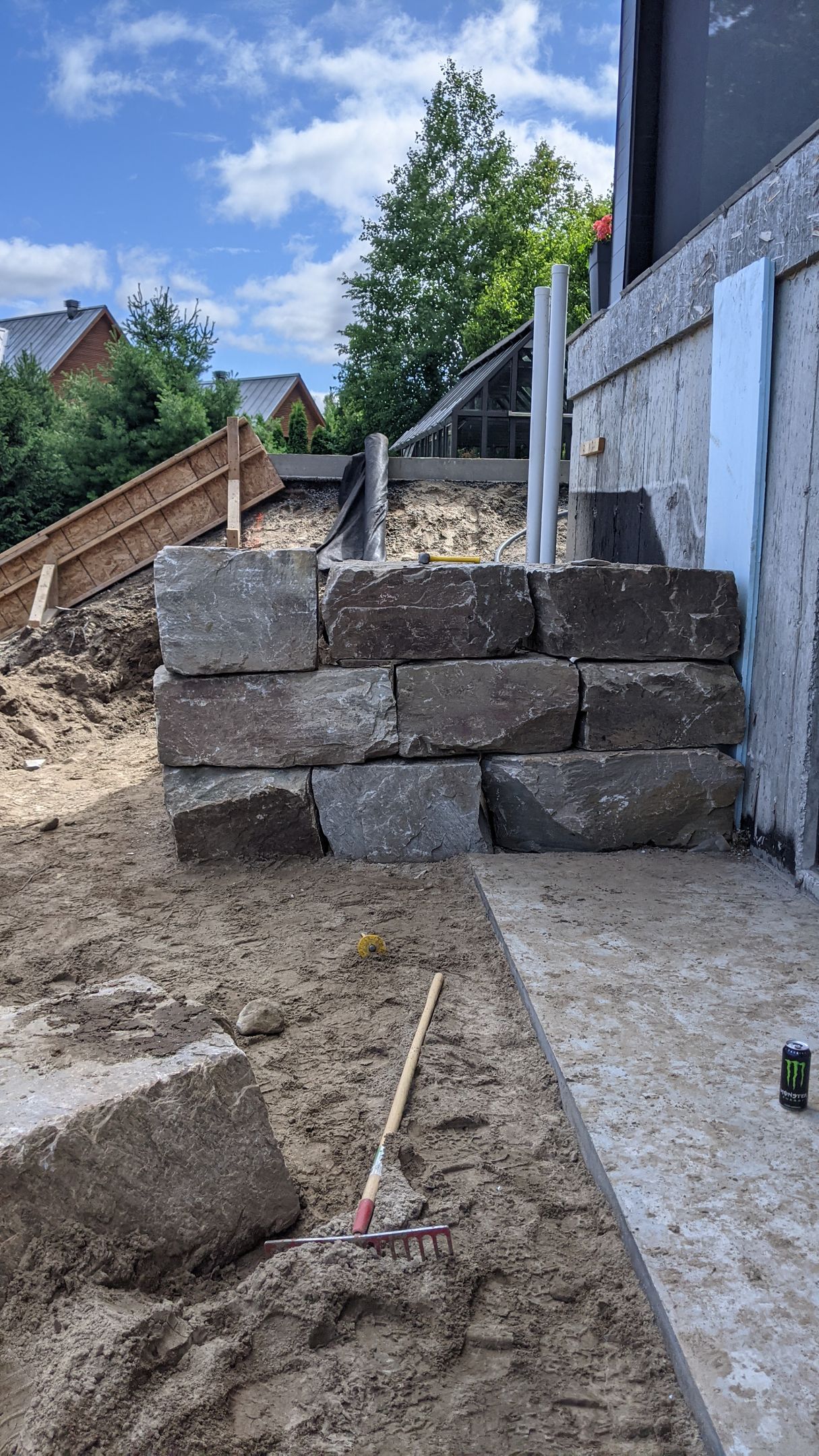 Un mur de pierre est en train d'être construit dans l'arrière-cour d'une maison.