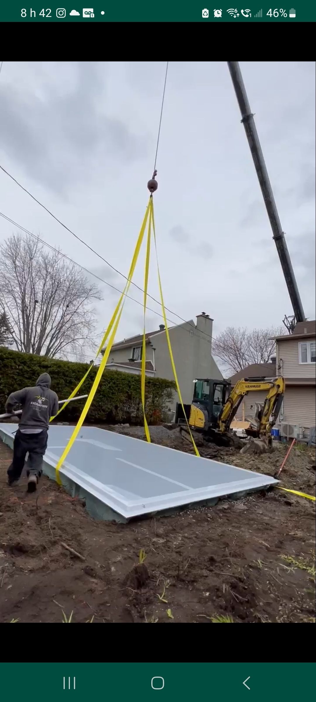 Une grue soulève un gros morceau de métal dans une cour.