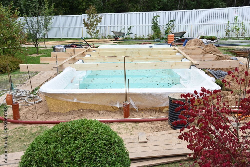 Une grande piscine est en cours de construction dans une cour arrière.