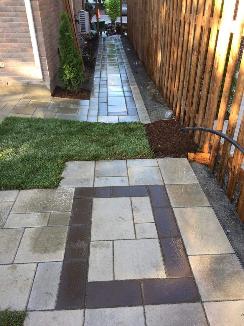 Une allée en briques avec une clôture en bois en arrière-plan.