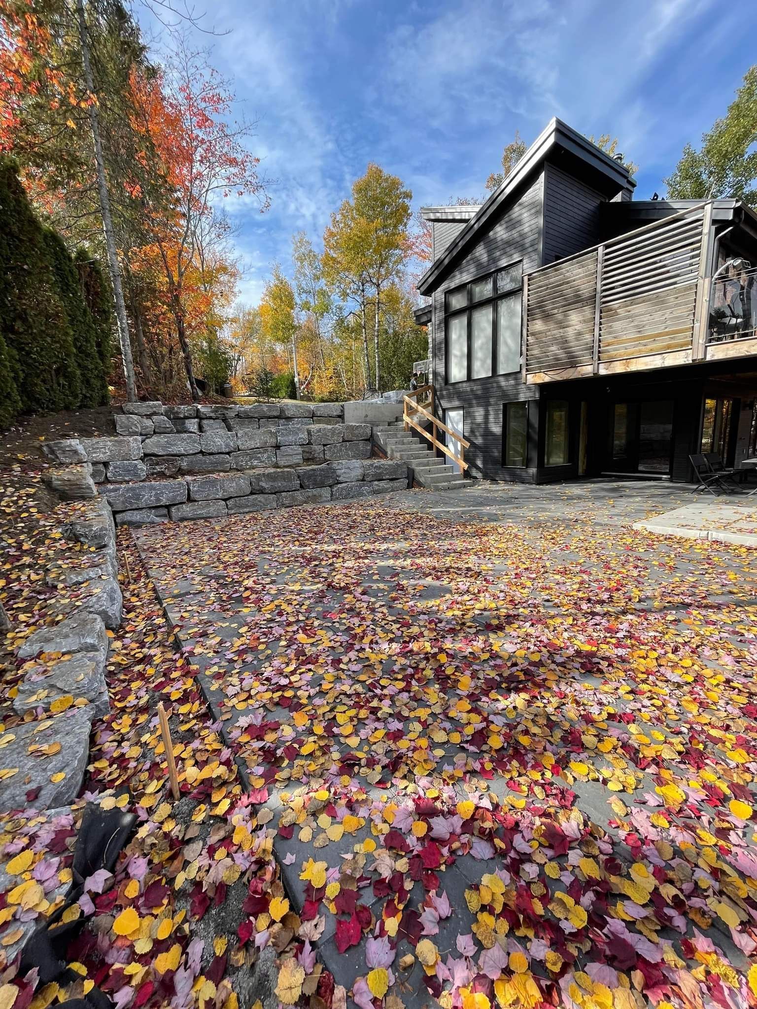 Une maison avec beaucoup de feuilles sur le sol devant elle.