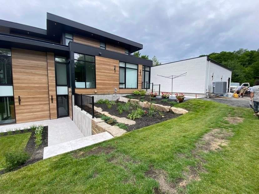 Une grande maison avec beaucoup de fenêtres est située au sommet d'une colline verdoyante.