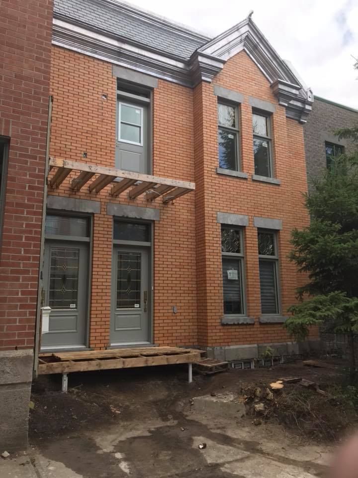 Un grand bâtiment en brique avec des portes et fenêtres grises