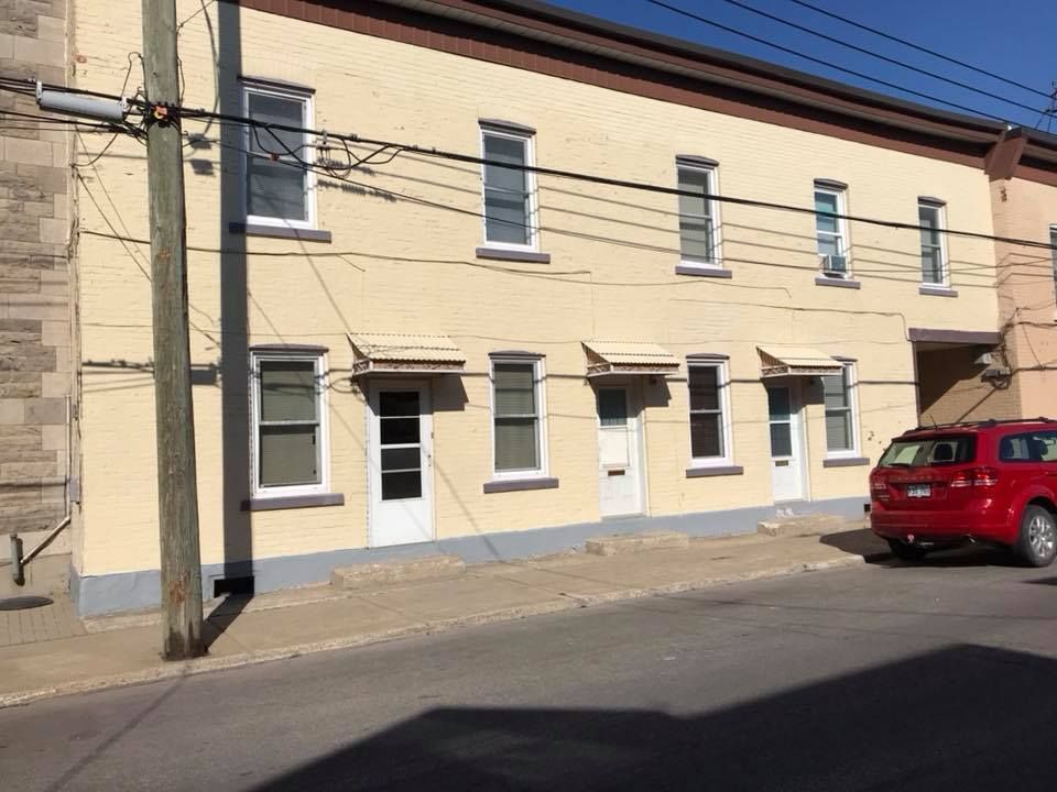 Une voiture rouge est garée devant un immeuble