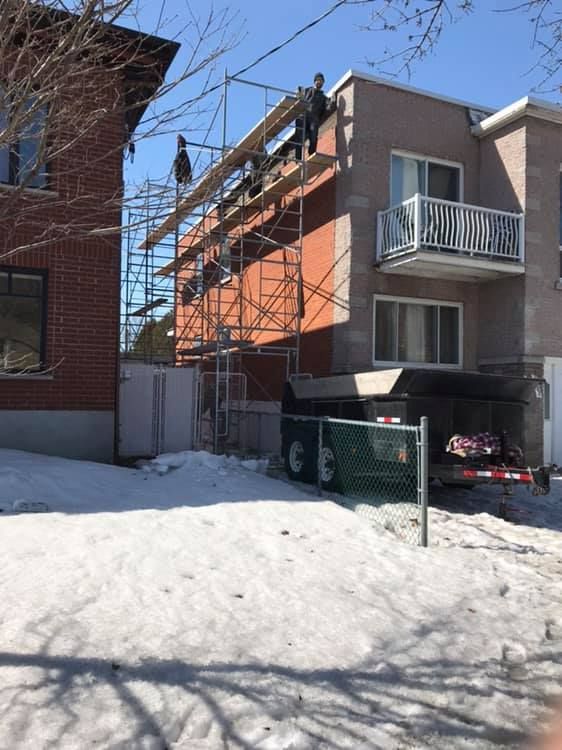 Un homme se tient sur le toit d'un immeuble entouré d'échafaudages.