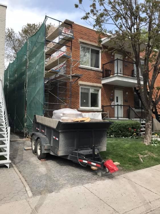 Un camion-benne est garé devant un bâtiment en brique.