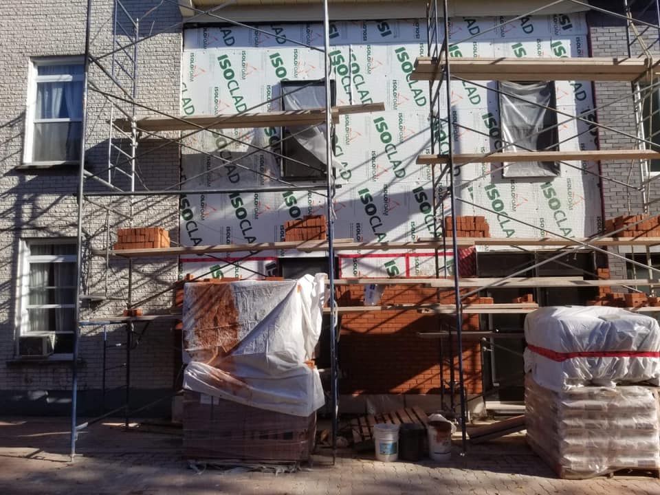 Un bâtiment est en cours de construction avec des échafaudages et des briques.