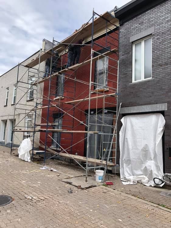 Un bâtiment est en train d'être peint avec des échafaudages devant lui.