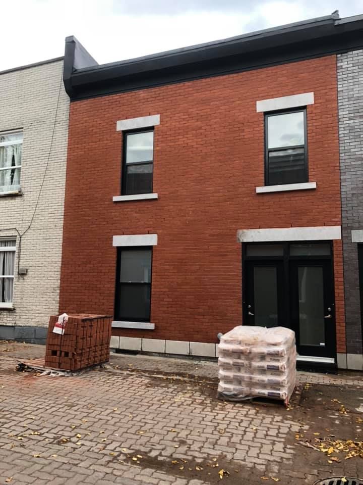 Un homme travaille sur une cheminée en brique avec une spatule.