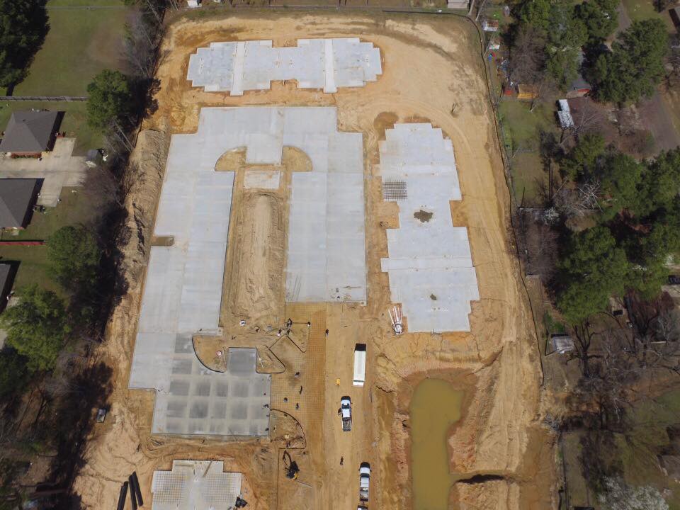 Aerial view of a construction site with concrete foundations and surrounding earthwork.