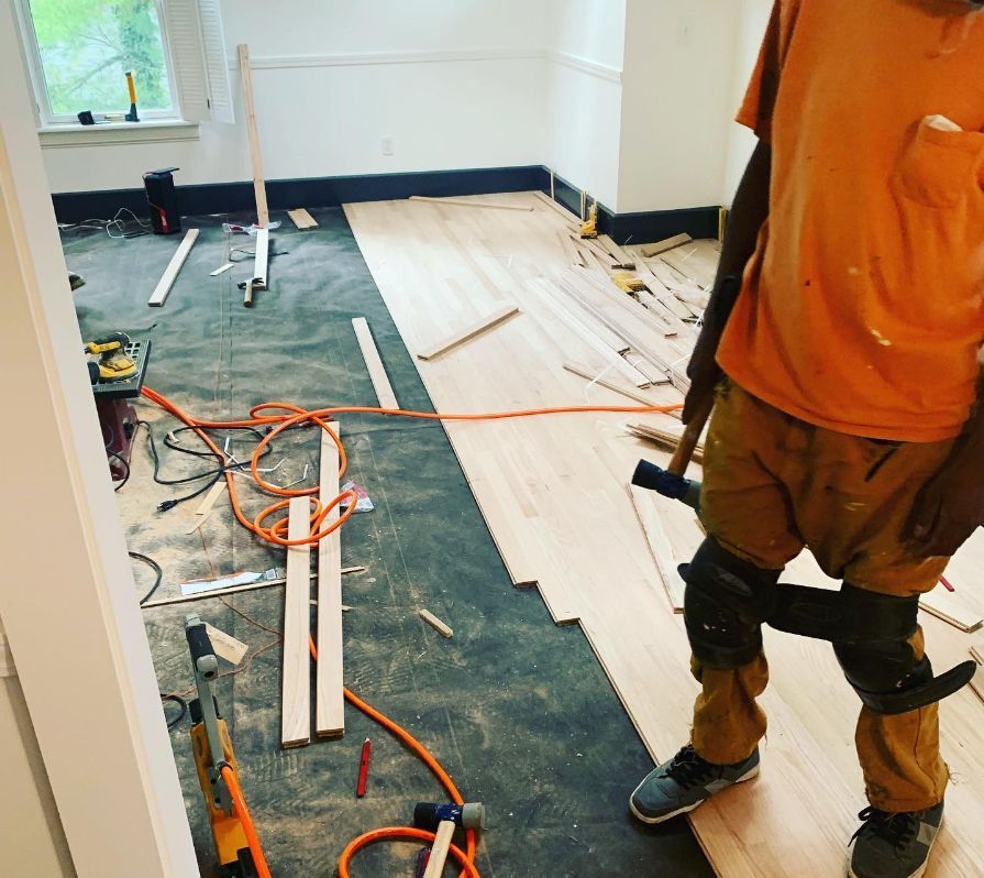 A man in an orange shirt is standing on a wooden floor