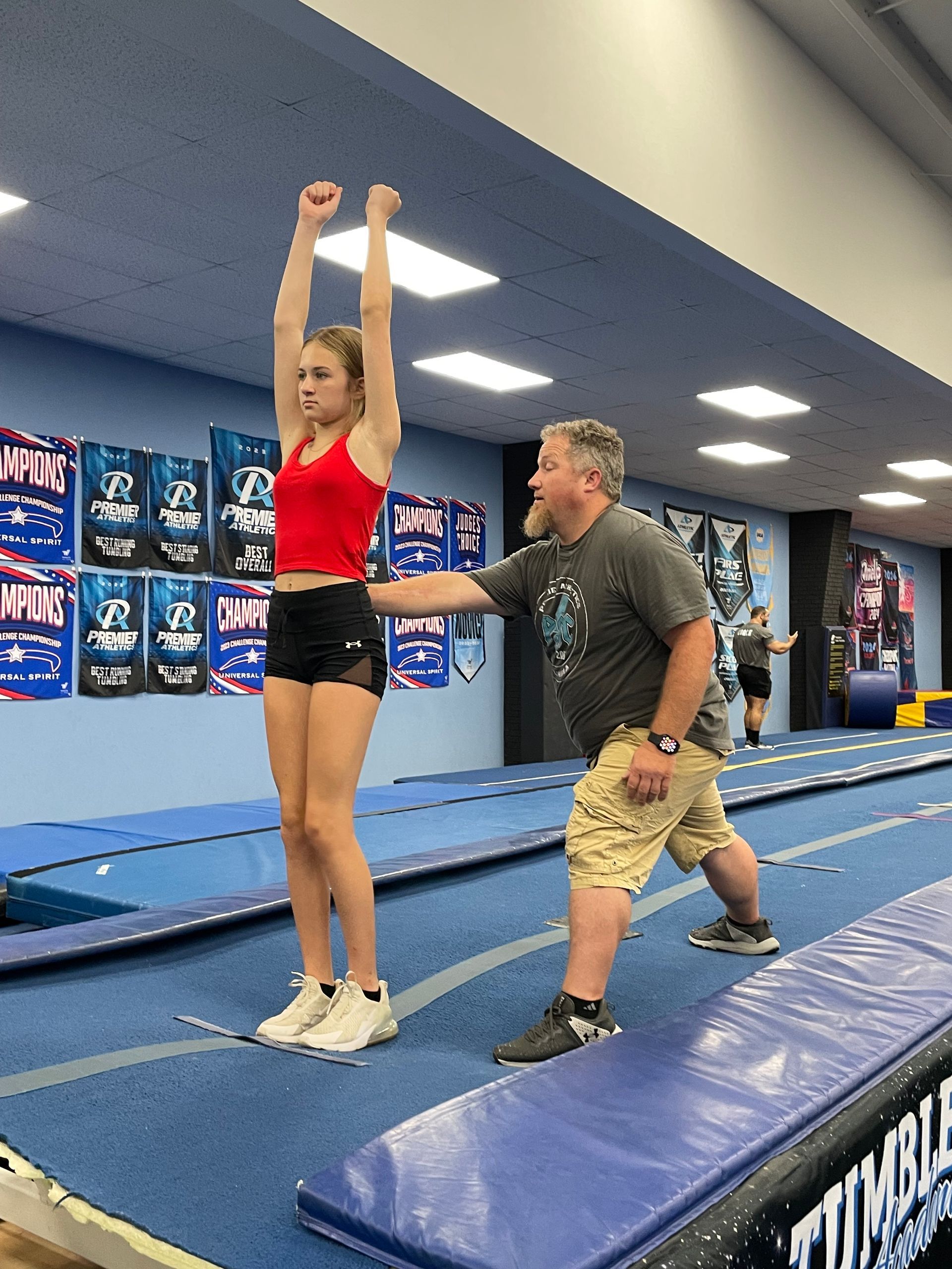 A man is helping a girl do a trick on a trampoline.