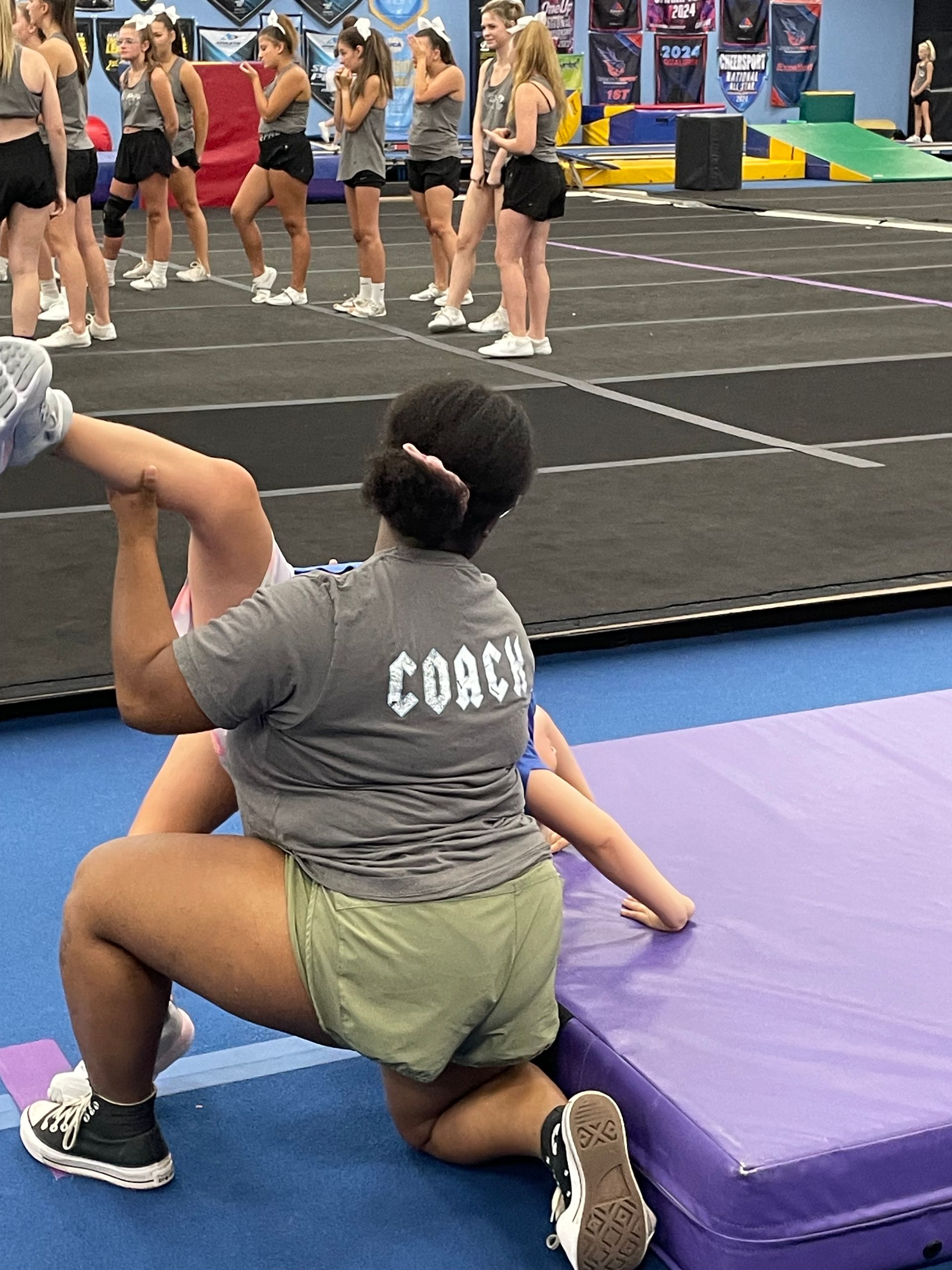 A woman wearing a coach shirt is kneeling on a mat