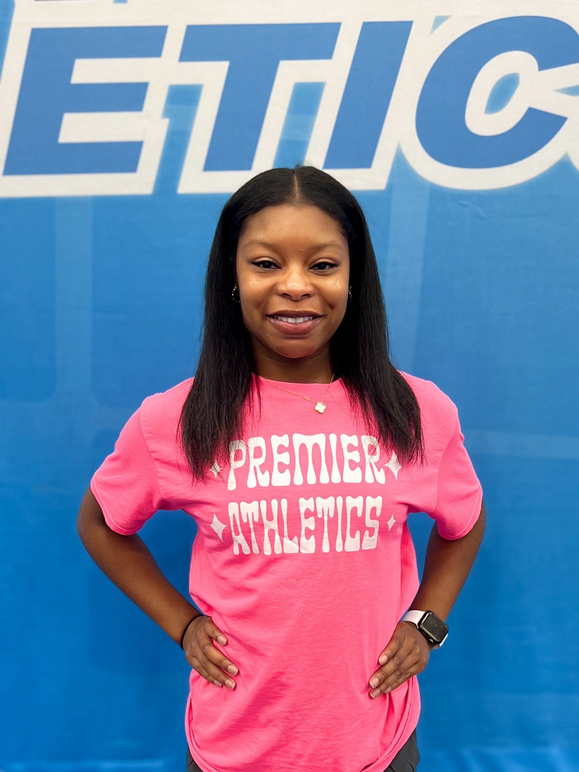 A woman wearing a pink shirt that says premier athletics