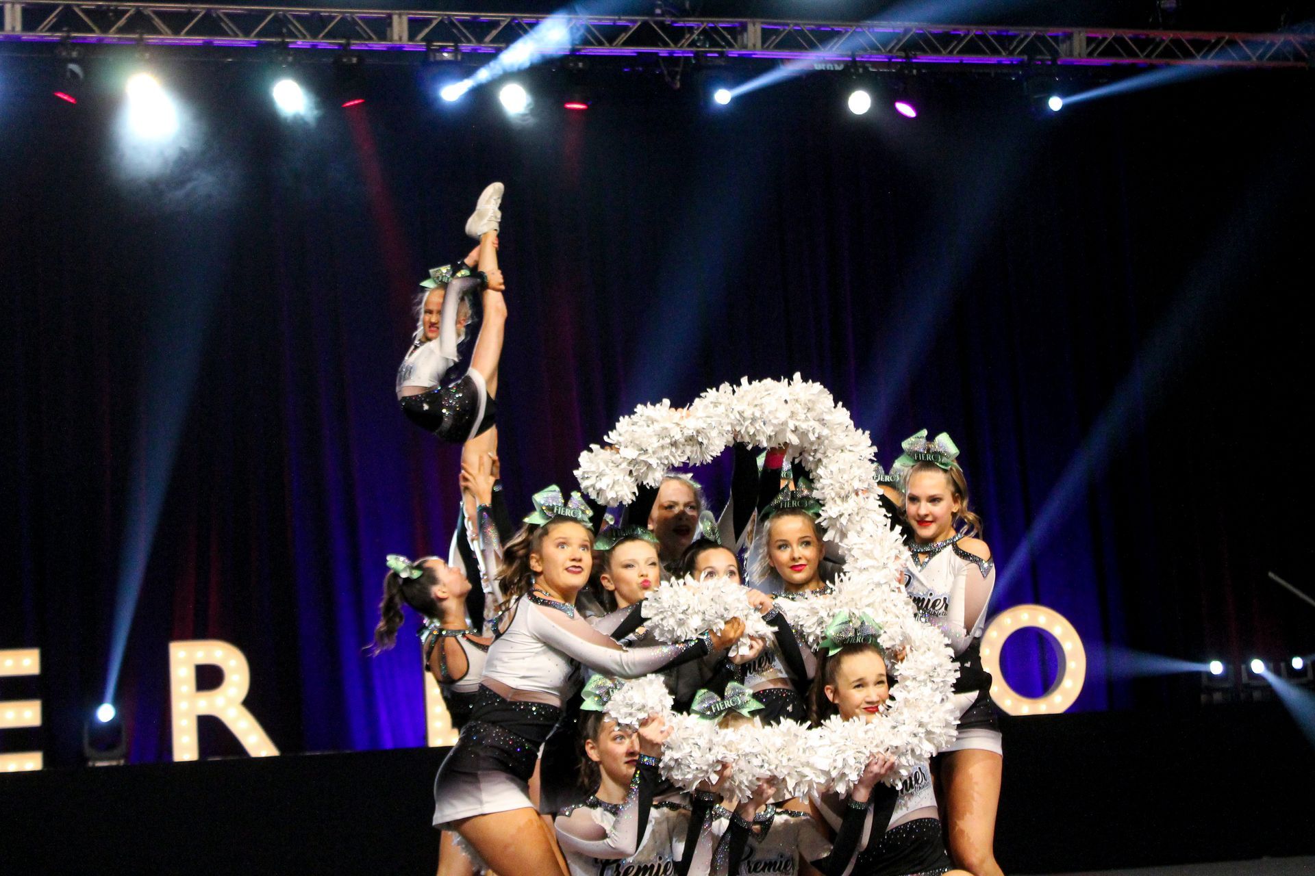 A group of cheerleaders are posing for a picture on a stage.