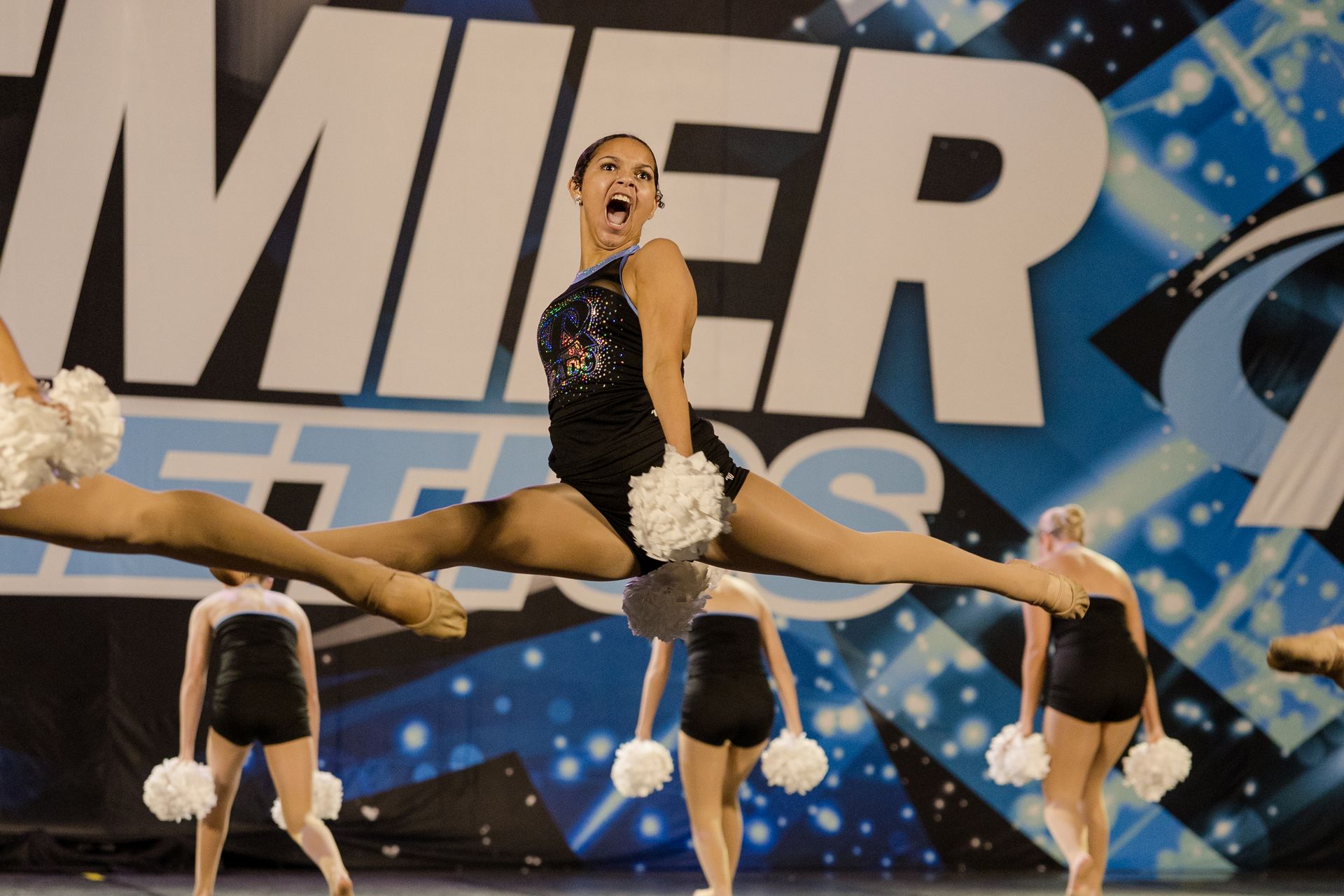A group of cheerleaders are performing in front of a sign that says 